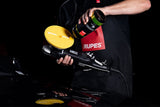 Anson PDR technician applying Rupes D-A FINE polishing compound to a yellow foam pad on a dual action polisher.