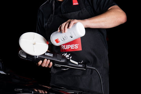 Anson PDR technician applying Rupes UNO Pure ultra-fine finishing polish to a white foam pad on a polishing tool.
