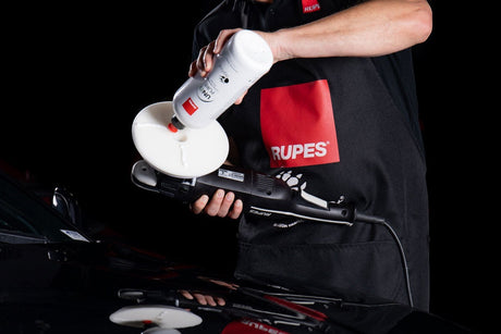 Anson PDR technician applying Rupes UNO Pure ultra-fine finishing polish to a white foam pad on a BigFoot polisher.