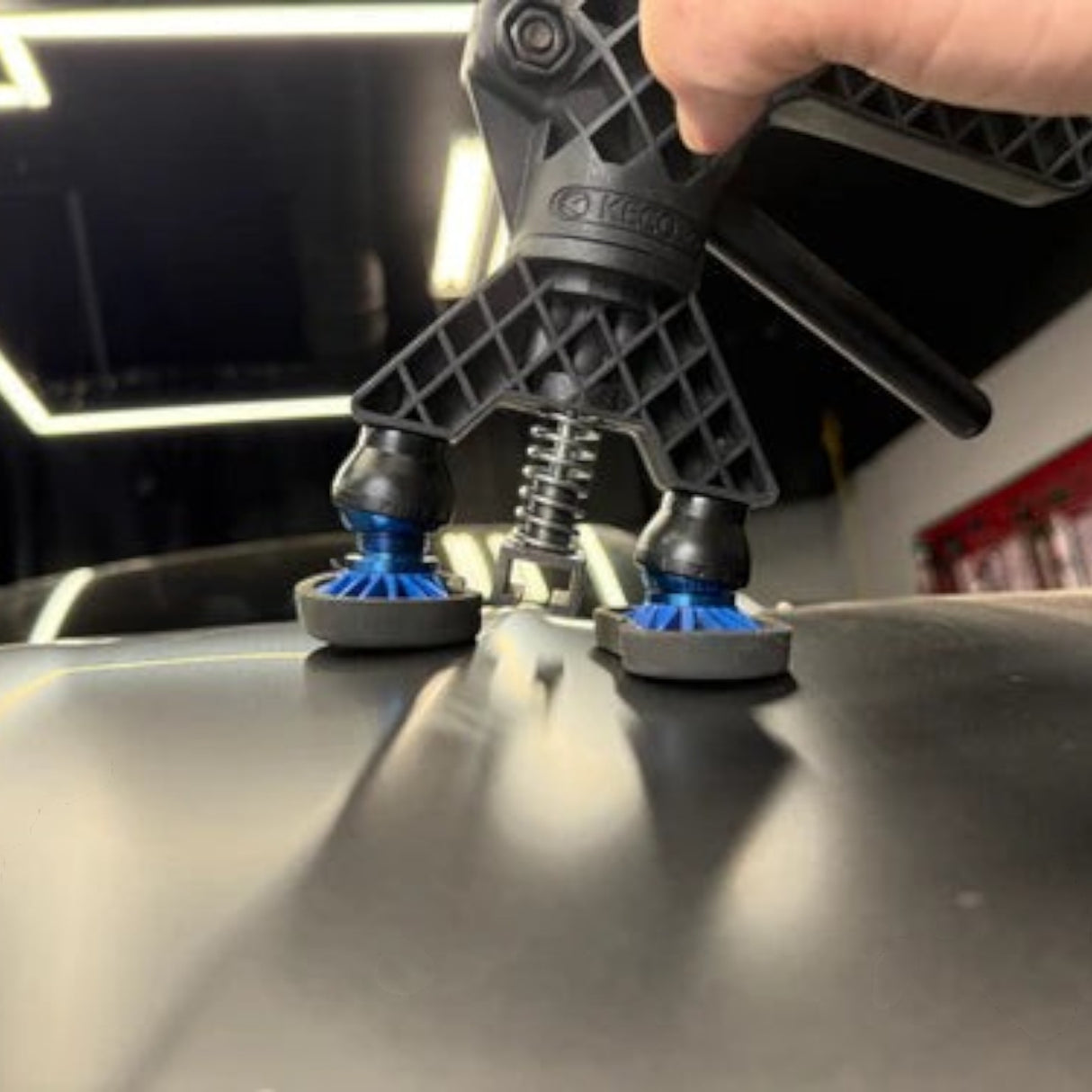 Anson PDR Black Plague Robo Legs with blue accents on a car panel for paintless dent repair.